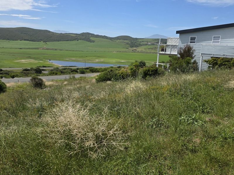 A view of the vacant residential land featuring natural vegetation with a distant landscape and water feature in the background.