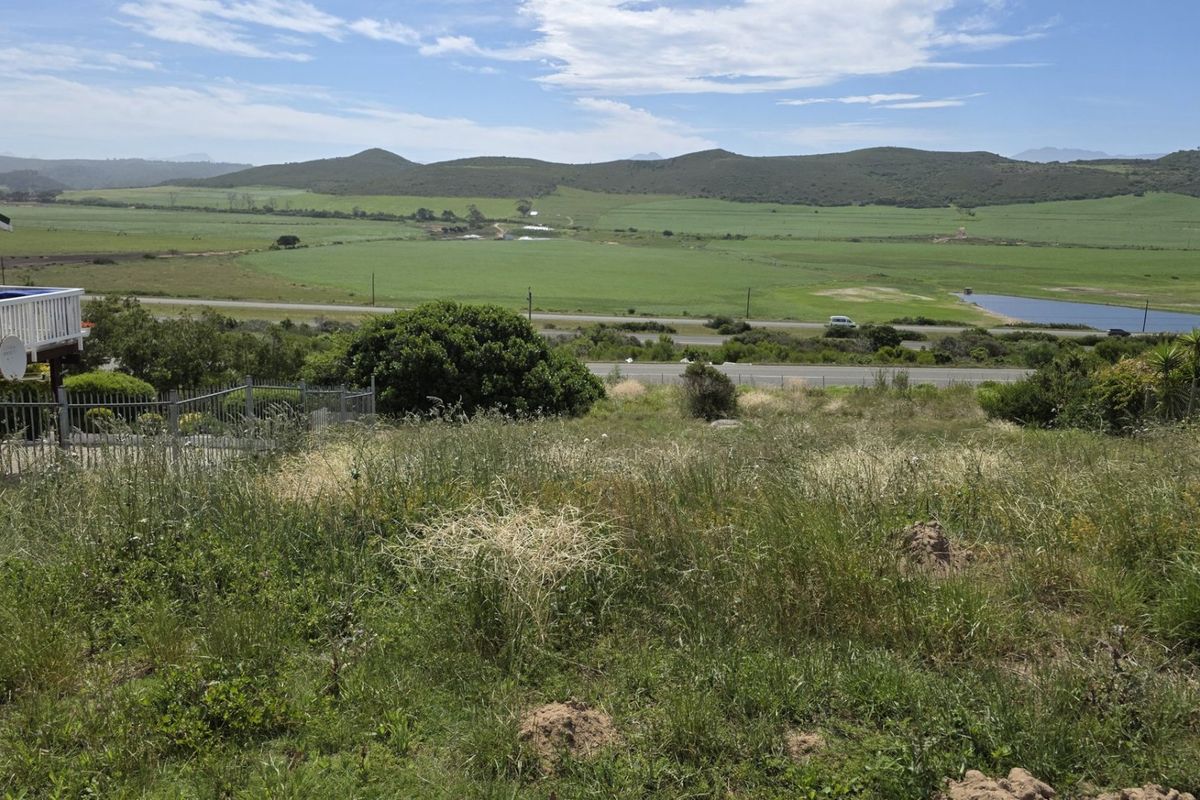 A scenic view overlooking open grassland, rolling hills, and a distant water body from the residential property.