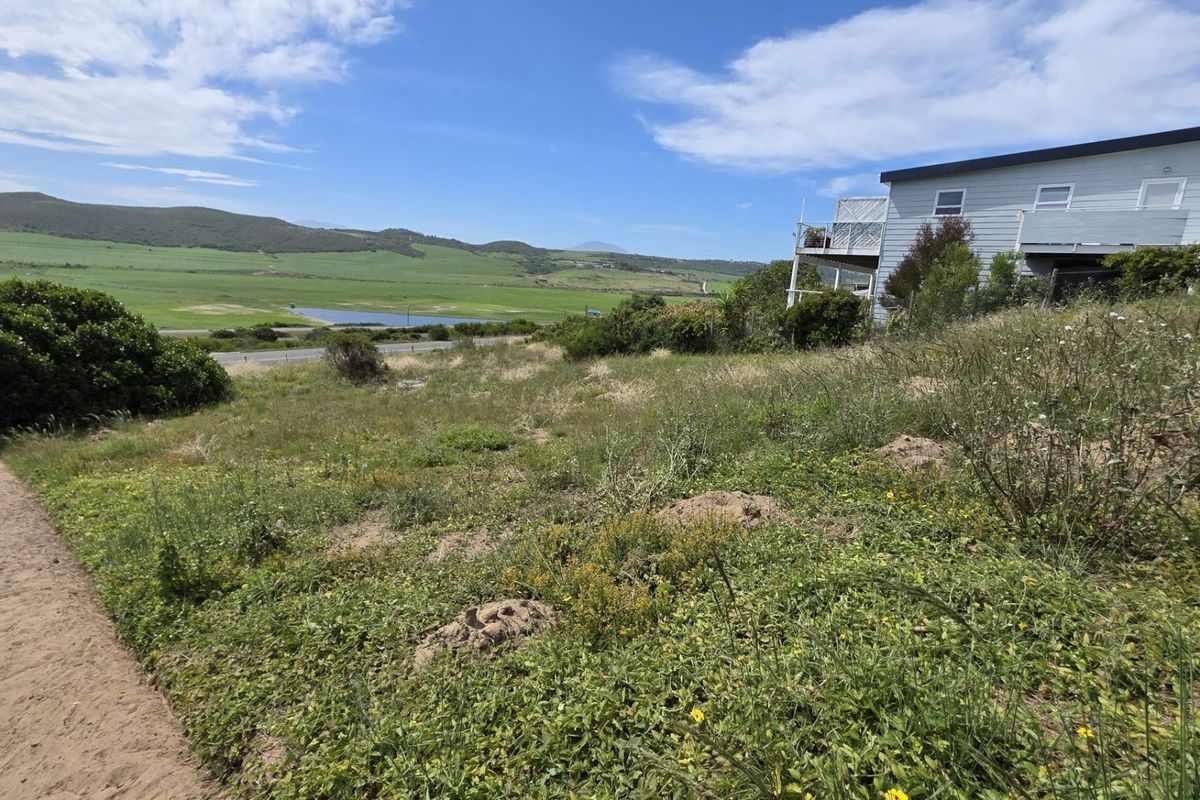 A scenic view of the surrounding landscape and valley, featuring sloped residential land with natural vegetation and an adjacent property.