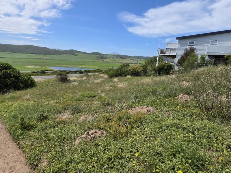 A scenic view of the surrounding landscape and valley, featuring sloped residential land with natural vegetation and an adjacent property.