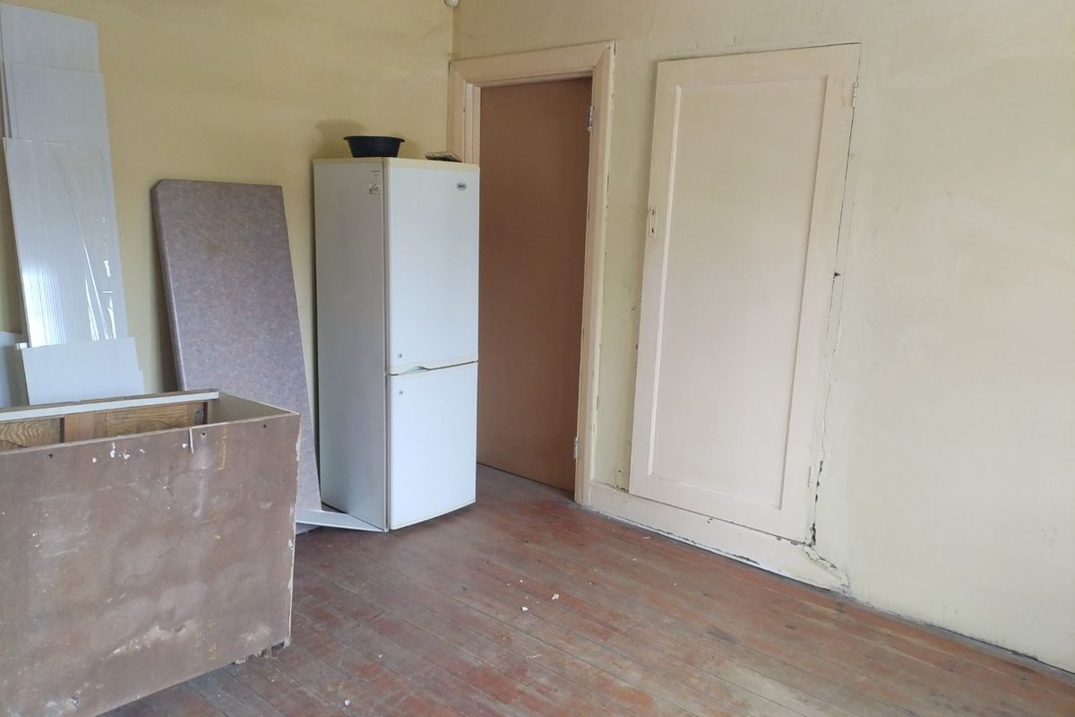 An empty room featuring original timber flooring and internal doors, currently requiring cosmetic updates and wall repairs.