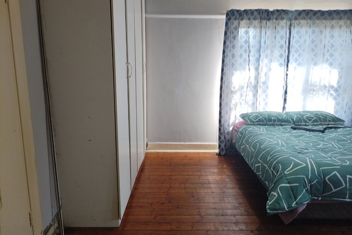 A bedroom featuring original timber flooring and built-in cupboards, requiring some cosmetic updates to the walls and skirting boards.