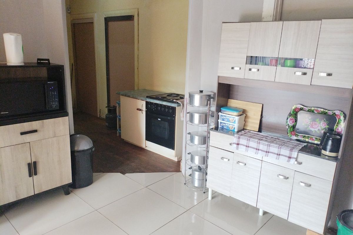 A functional kitchen area featuring built-in cabinetry, a stove with oven, and tiled flooring, providing a practical space for meal preparation.