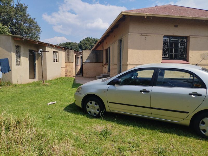 Rear view of the property showing the main house and an outbuilding with a lawn area and metal security features.