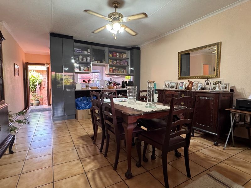 Open-plan dining and kitchen area featuring tiled flooring, a ceiling fan, and modern dark-toned built-in cabinetry.