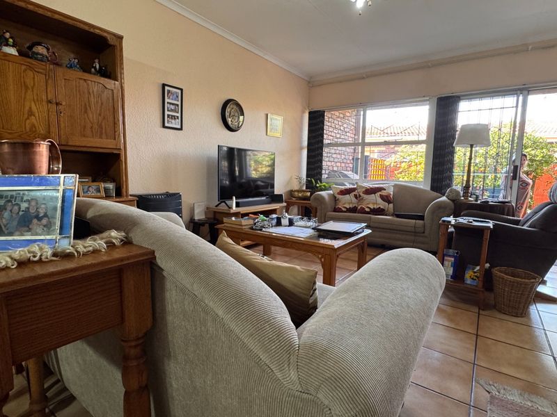 A comfortable living room featuring tiled flooring and large sliding glass doors that provide access to the outdoor area.