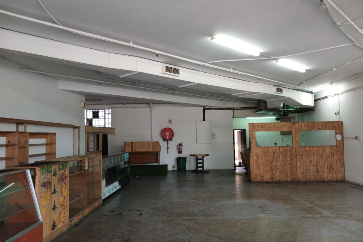 Open plan commercial space featuring exposed ducting, fluorescent lighting, and concrete flooring, suitable for retail or office use.