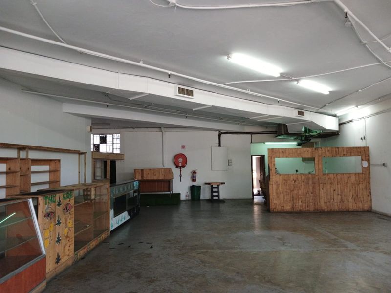 Open plan commercial space featuring exposed ducting, fluorescent lighting, and concrete flooring, suitable for retail or office use.