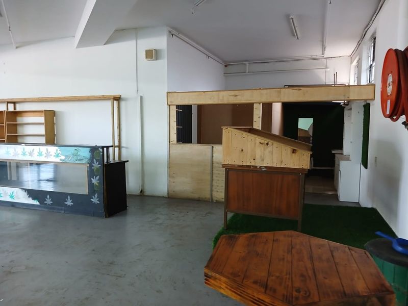Open plan commercial space featuring concrete flooring, fluorescent lighting, and built-in wooden partitions, suitable for retail or office use.