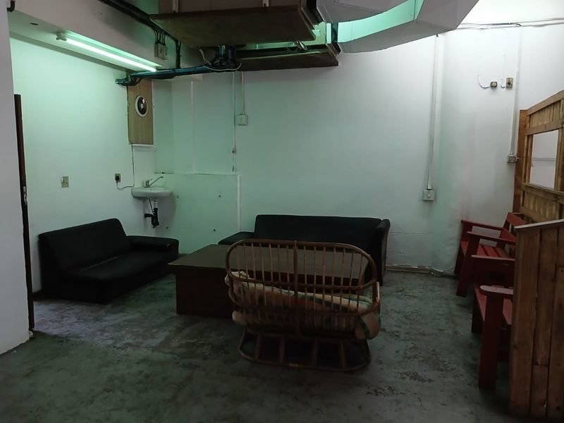 A utilitarian commercial space featuring exposed ducting, concrete flooring, and a wall-mounted basin, suitable for renovation or repurposing.
