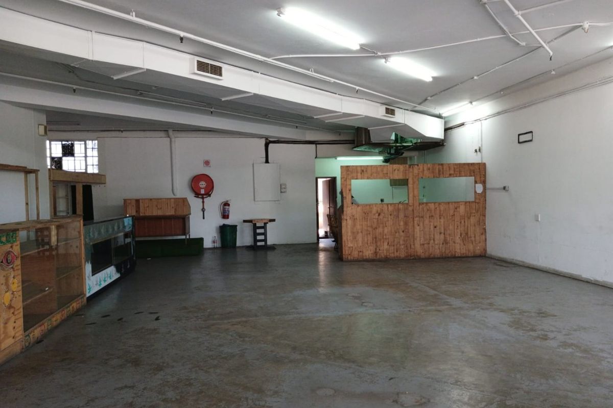 Spacious open-plan commercial area featuring exposed ducting, concrete flooring, and functional partition walls, suitable for various business layouts.