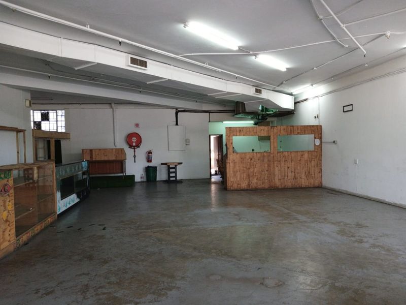 Spacious open-plan commercial area featuring exposed ducting, concrete flooring, and functional partition walls, suitable for various business layouts.