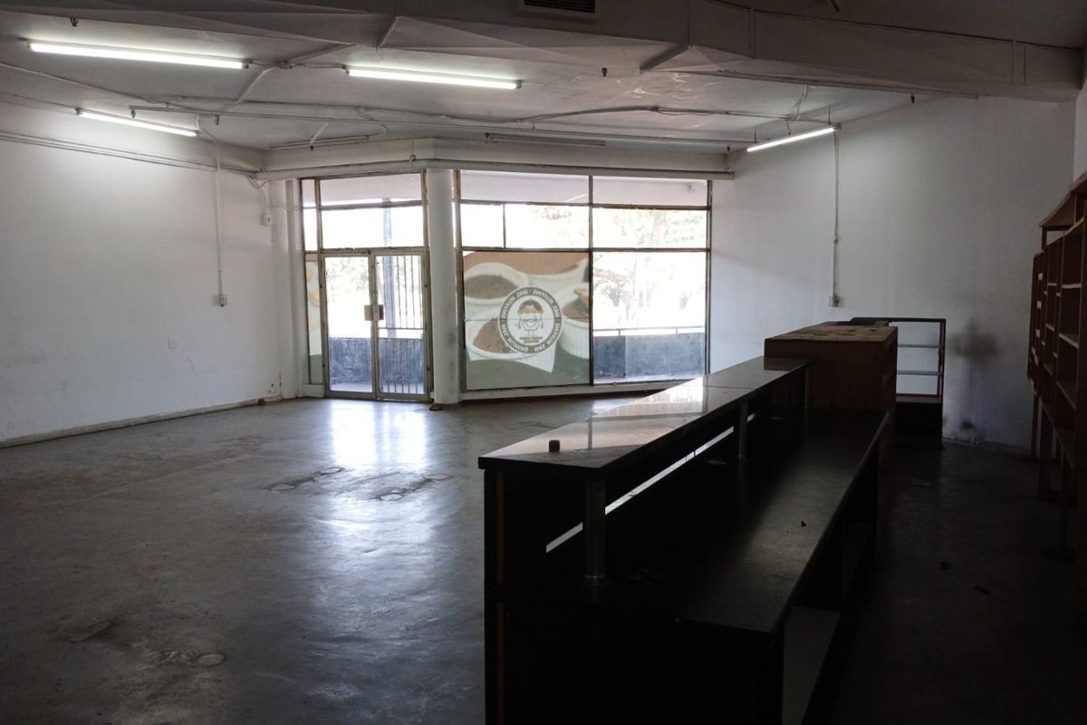 Spacious open-plan commercial unit featuring large storefront windows, exposed ceiling ducting, and a built-in service counter, suitable for retail or office use.