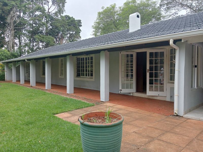 A spacious covered patio area featuring tiled flooring, support columns, and multiple sets of french doors leading into the home.