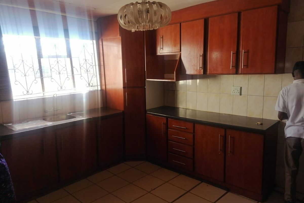 A functional kitchen featuring wooden cabinetry, dark countertops, and tiled flooring, offering a classic layout with ample storage space.