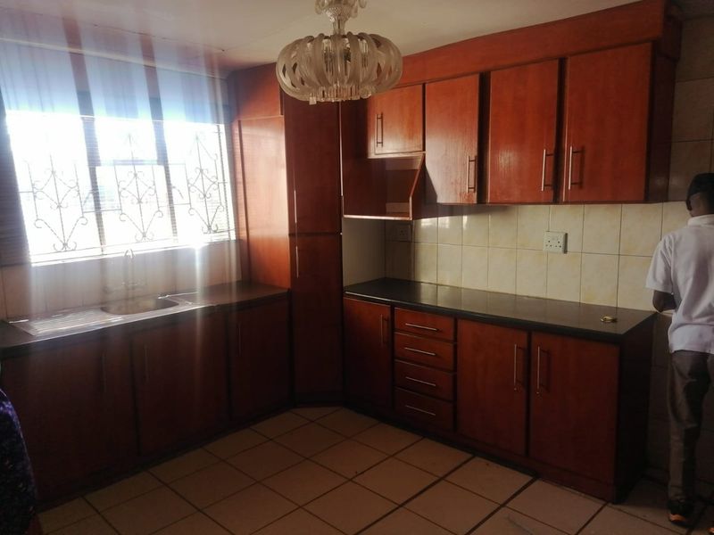 A functional kitchen featuring wooden cabinetry, dark countertops, and tiled flooring, offering a classic layout with ample storage space.