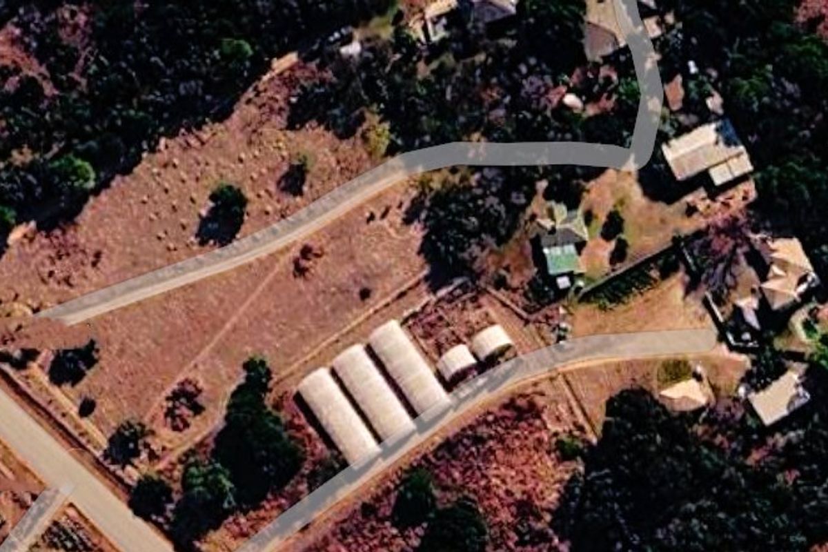 Aerial view of the farm property showing the main access road, multiple greenhouses, and existing outbuildings on the land.