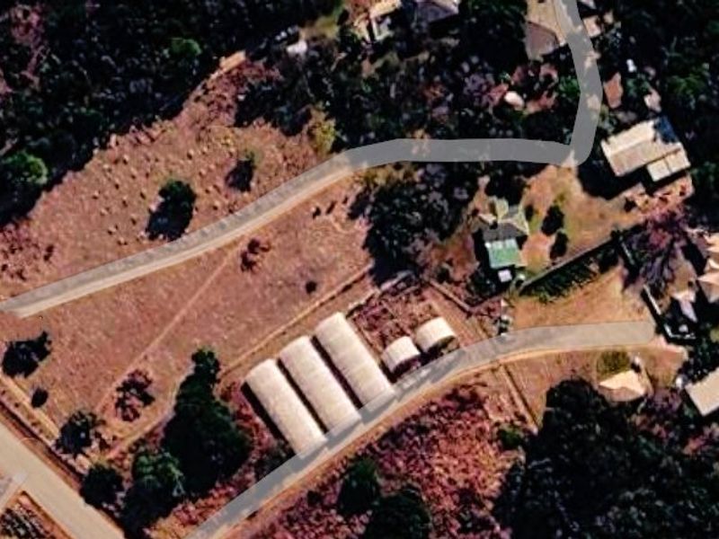 Aerial view of the farm property showing the main access road, multiple greenhouses, and existing outbuildings on the land.