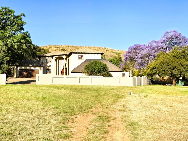 A wide-angle view of the farm property featuring a multi-level residence with a combination of tiled and thatched roofing, enclosed by a perimeter wall.