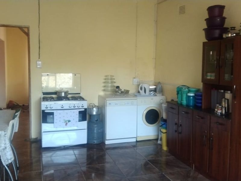 A functional kitchen area featuring tiled flooring, built-in cabinetry, and a gas stove, requiring cosmetic updates to modernize the space.