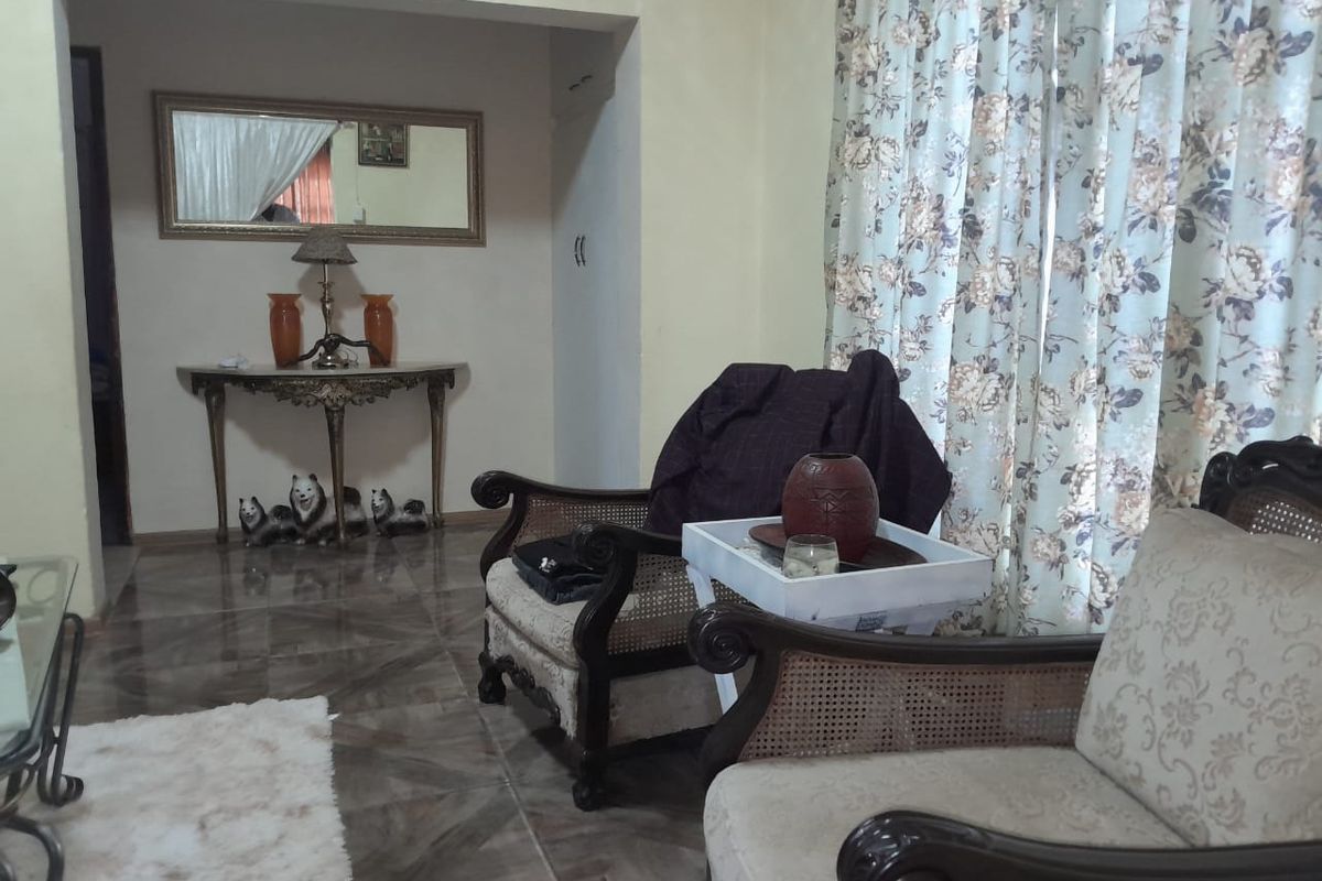 A living room area featuring tiled flooring and a cased opening leading to an adjacent space.