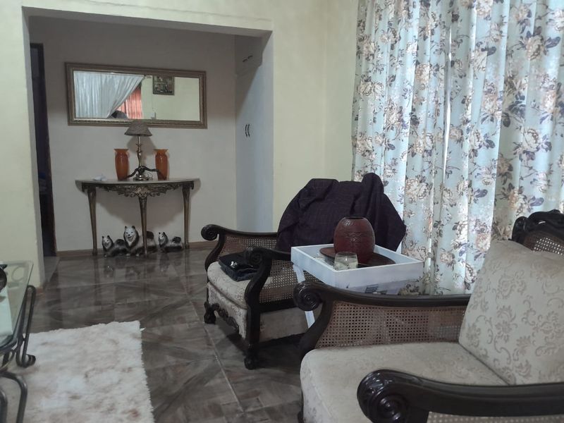 A living room area featuring tiled flooring and a cased opening leading to an adjacent space.