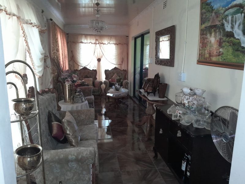 A long living room featuring tiled flooring, coved ceilings, and a sliding glass door providing access to the exterior.