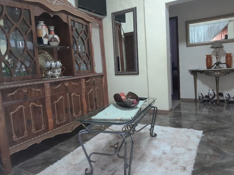 A living room area featuring tiled flooring and an open archway leading to an adjacent space.