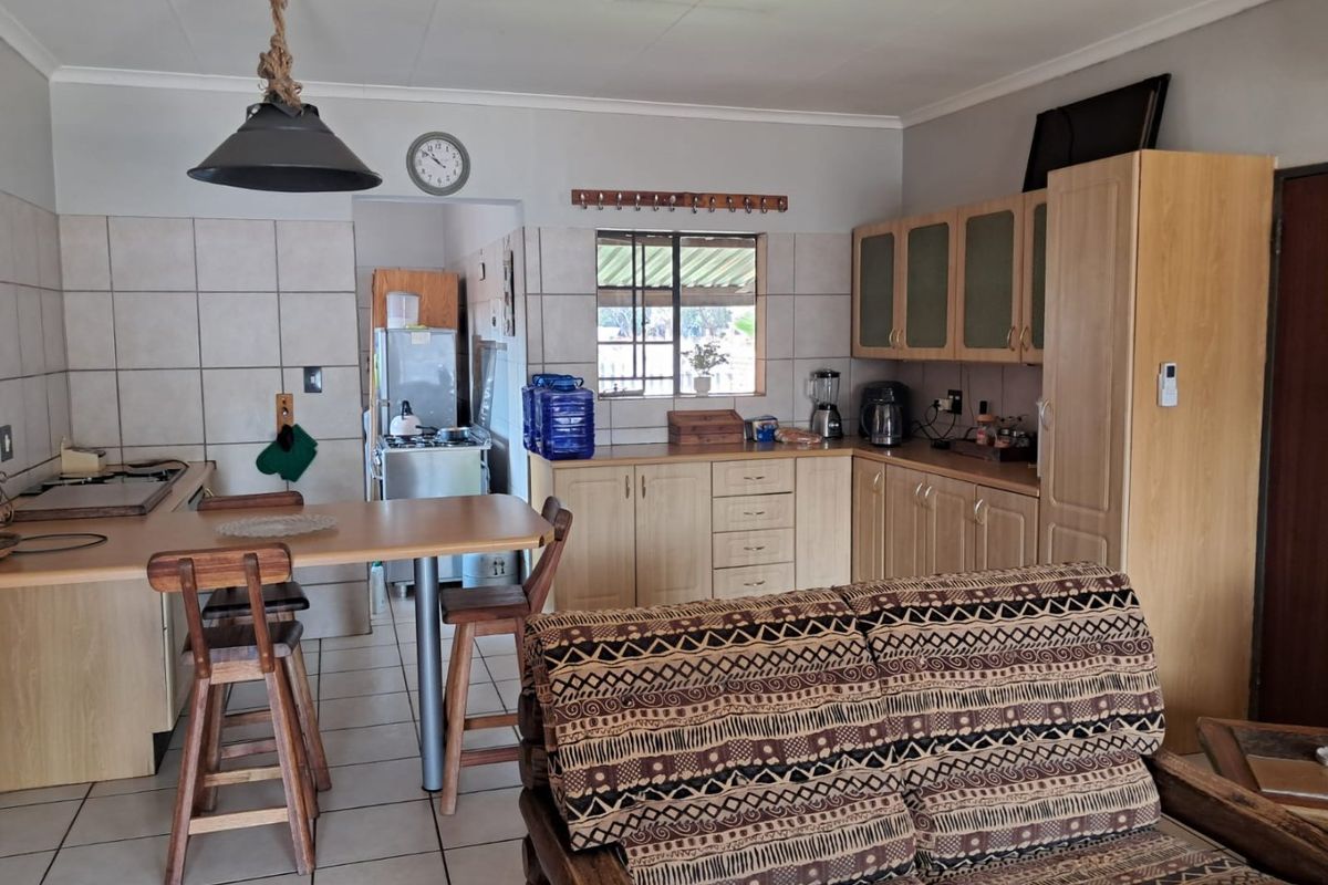 Open-plan kitchen and living area featuring built-in cabinetry, tiled flooring, and a breakfast counter, offering a functional layout with potential for modern updates.