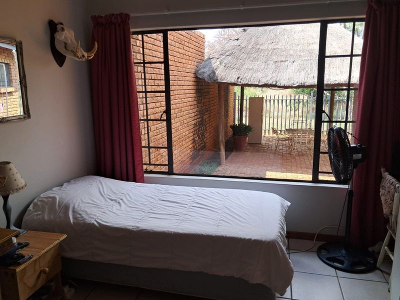 A bedroom featuring tiled flooring and a large window providing a view of the outdoor patio area.