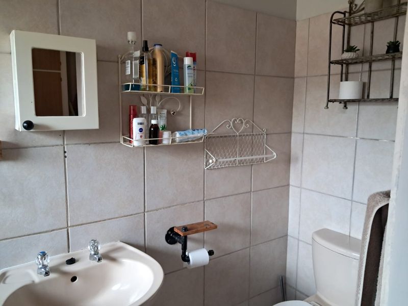 A functional bathroom featuring tiled walls, a pedestal basin, and a standard toilet, providing a practical space with basic fixtures.