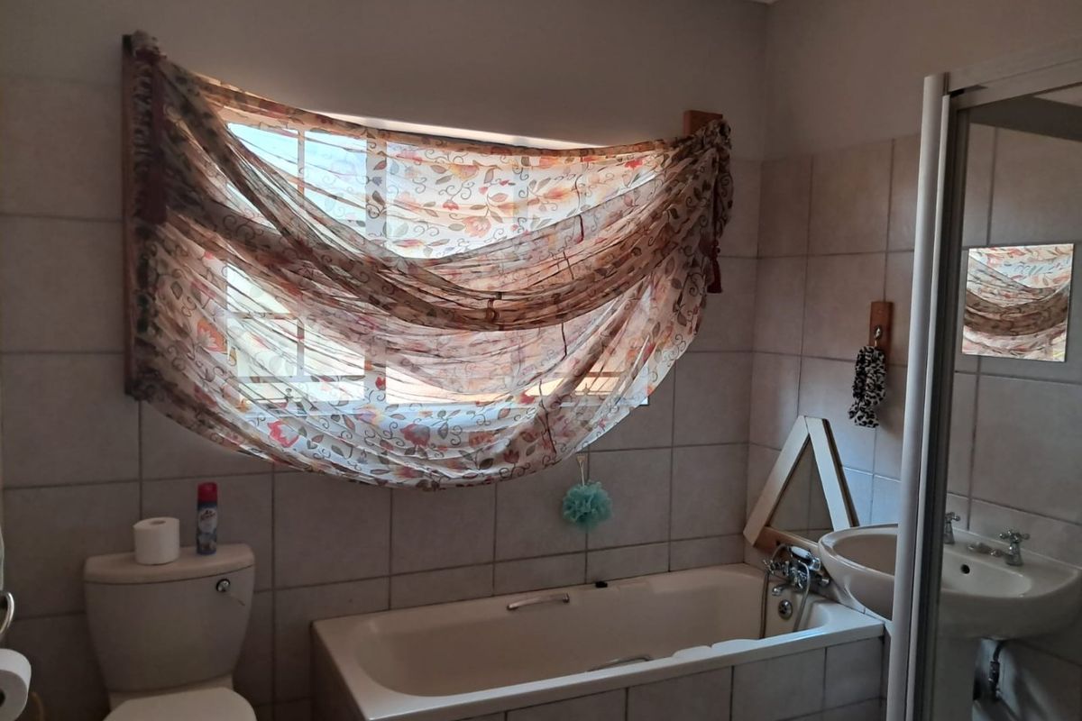 A functional bathroom featuring a built-in bathtub, wall-mounted basin, toilet, and tiled wall finishes.