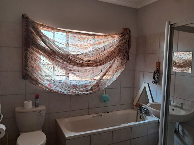 A functional bathroom featuring a built-in bathtub, wall-mounted basin, toilet, and tiled wall finishes.