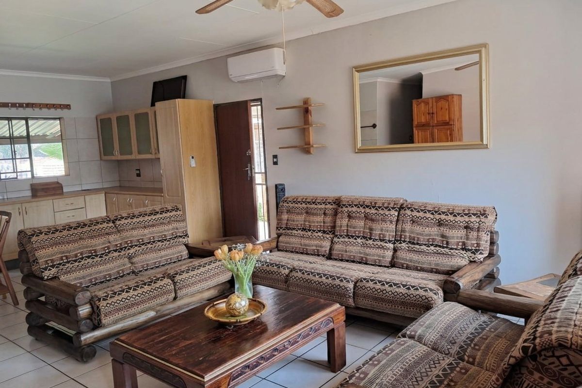 Open-plan living area featuring tiled flooring, a ceiling fan, and an integrated kitchen space with wooden cabinetry.