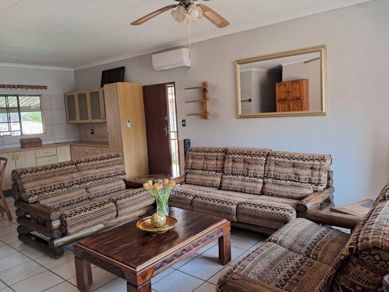Open-plan living area featuring tiled flooring, a ceiling fan, and an integrated kitchen space with wooden cabinetry.
