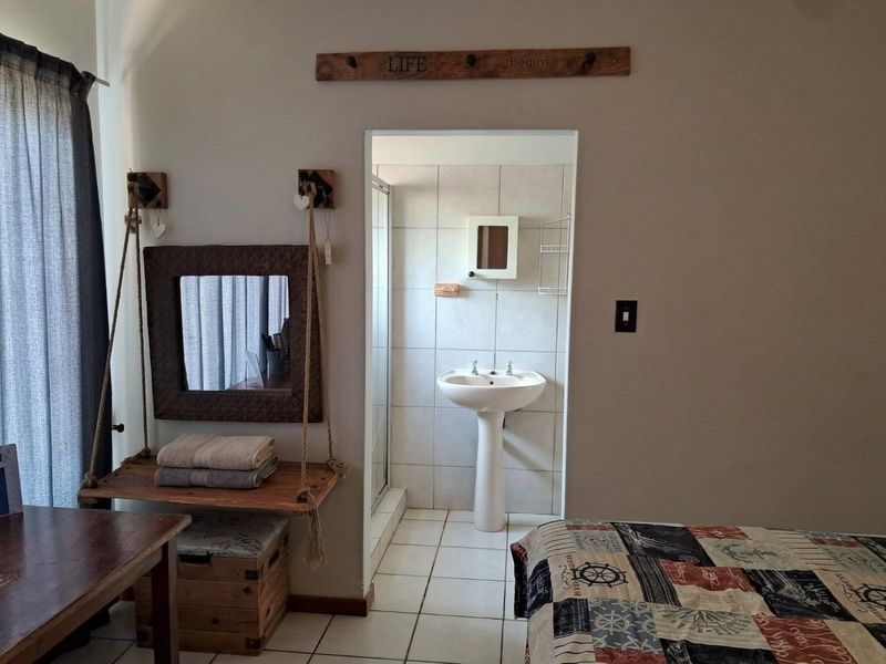Bedroom featuring an en-suite bathroom with a pedestal basin, tiled flooring, and a shower enclosure.