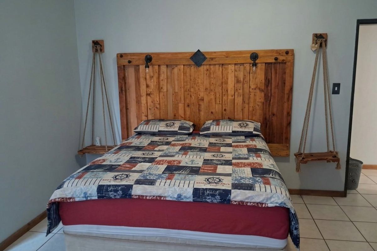 A bedroom featuring tiled flooring and a custom wooden headboard with integrated lighting fixtures.