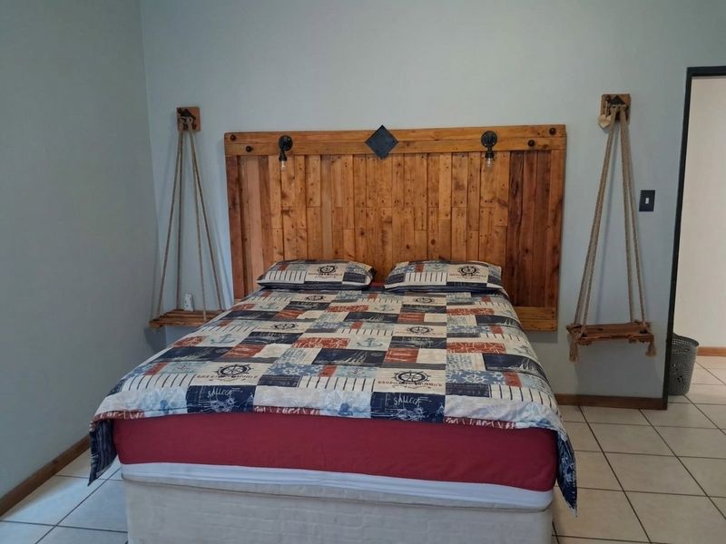 A bedroom featuring tiled flooring and a custom wooden headboard with integrated lighting fixtures.