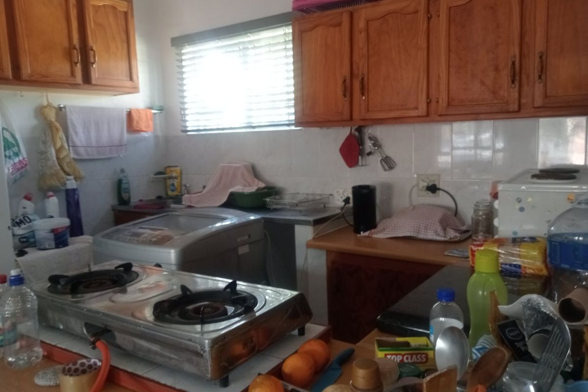 A functional kitchen featuring wooden cabinetry, tiled backsplash, and ample counter space, offering a practical layout for daily meal preparation.