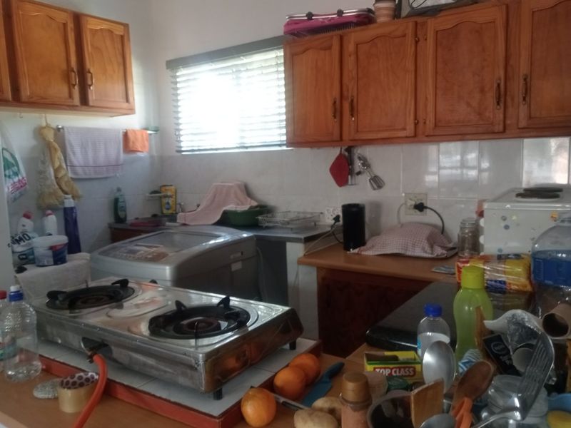 A functional kitchen featuring wooden cabinetry, tiled backsplash, and ample counter space, offering a practical layout for daily meal preparation.