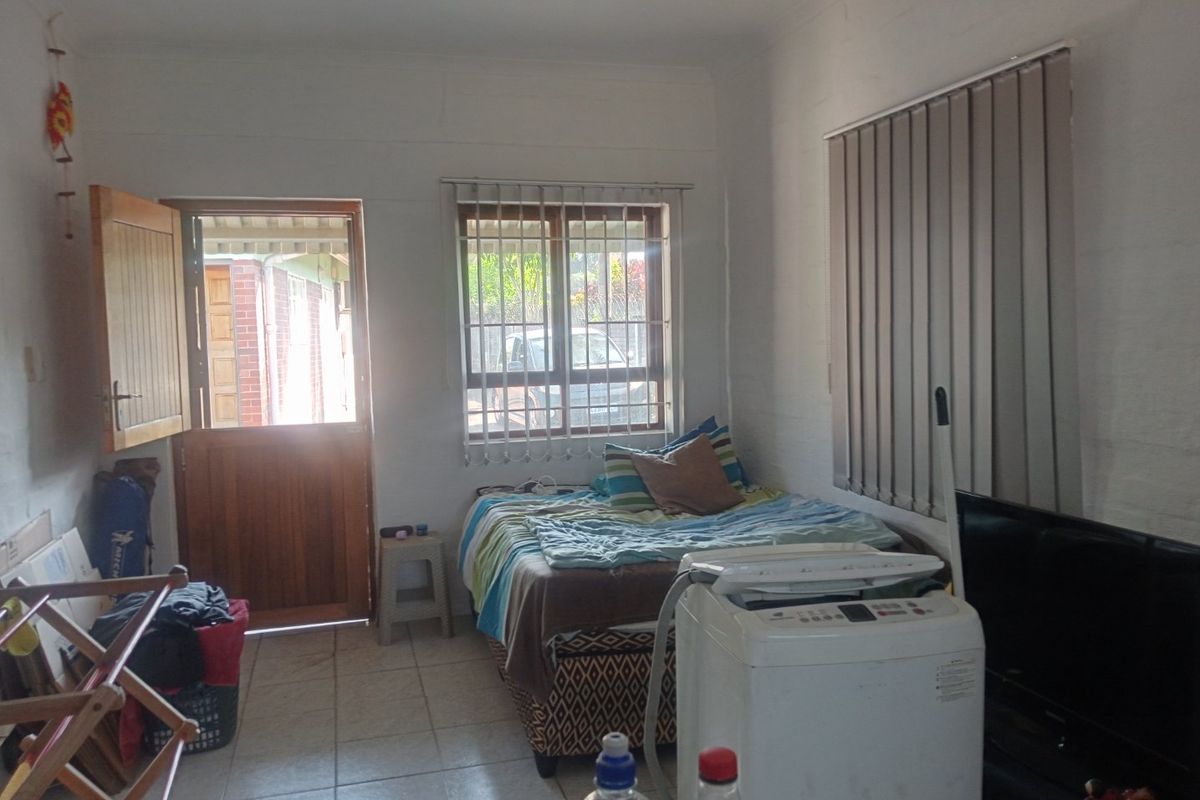 A bedroom featuring tiled flooring, vertical blinds, and a wooden exterior door with security bars on the window.