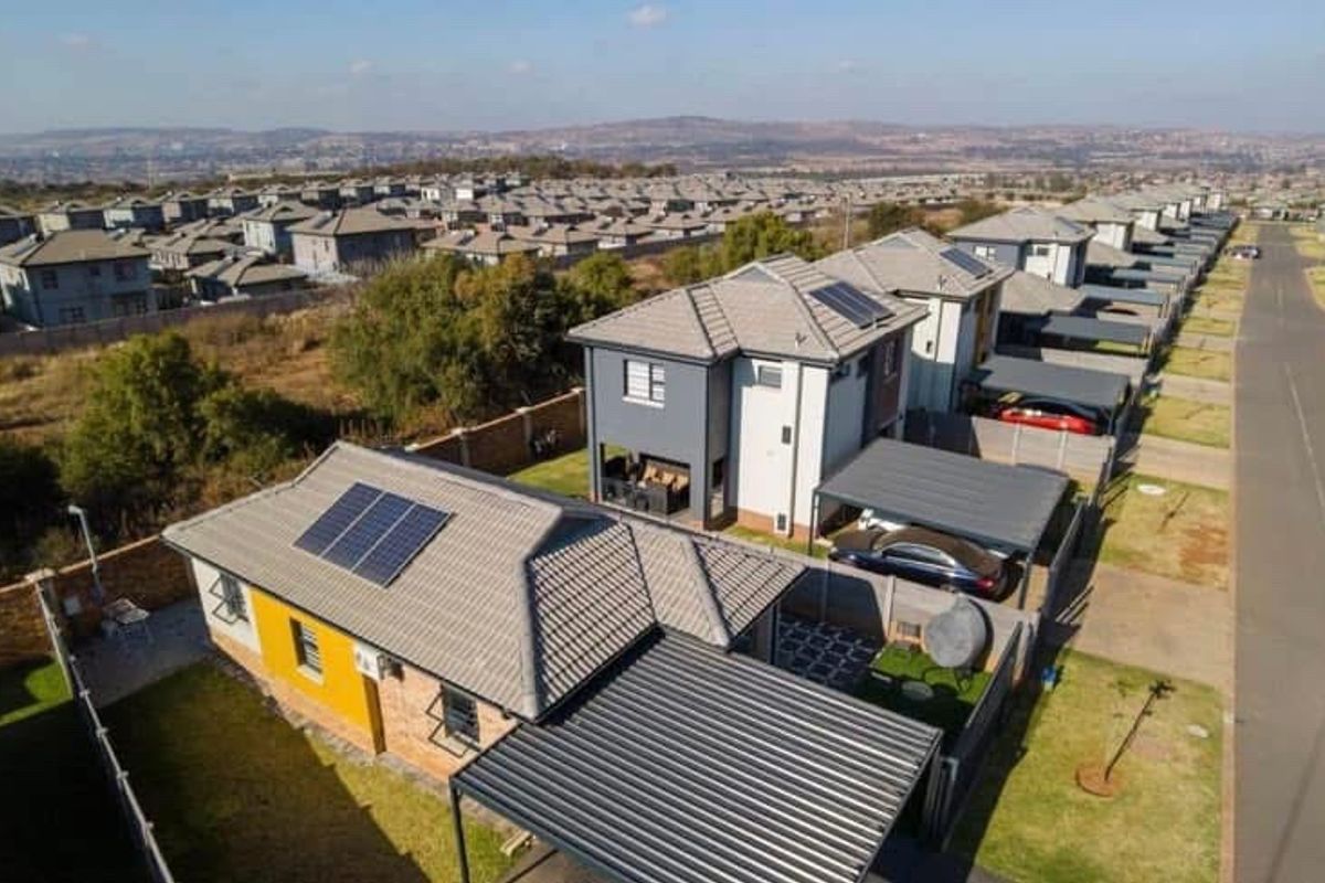 Aerial view of a residential estate featuring modern homes with tiled roofs, solar panels, and private carports in a well-planned suburban setting.