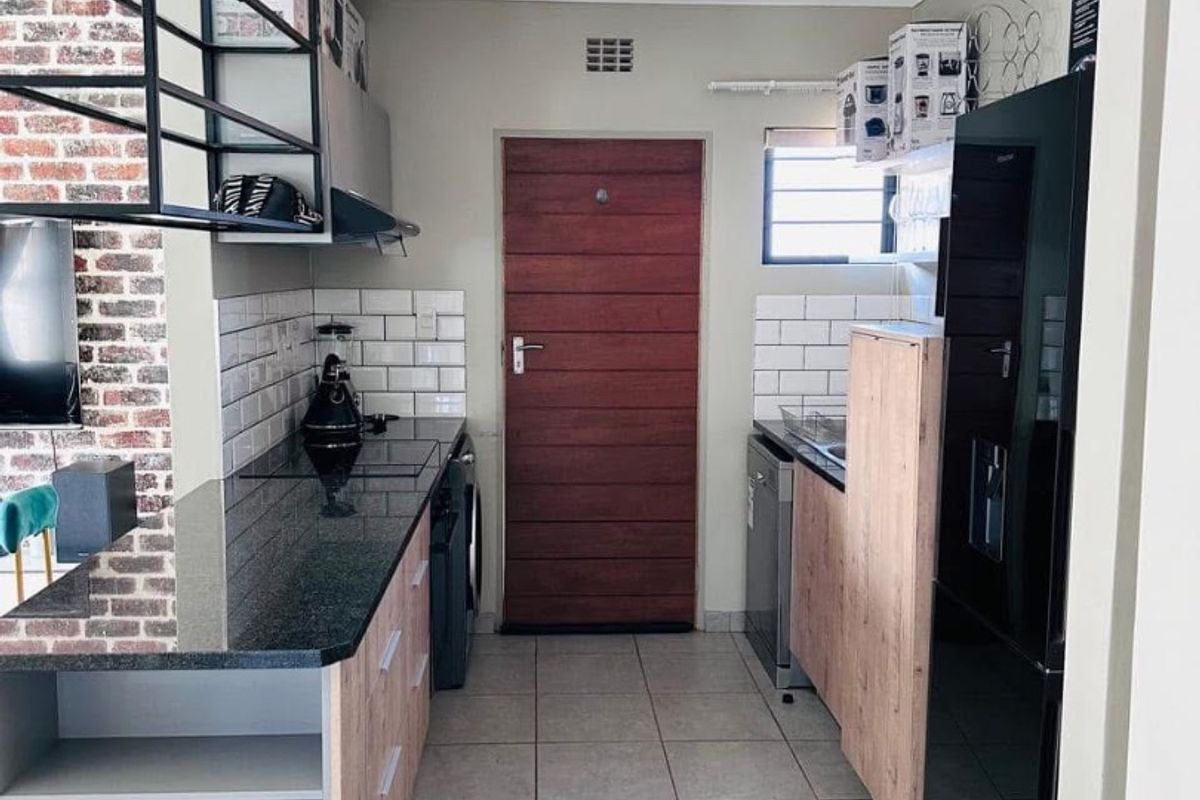 Modern kitchen featuring granite countertops, subway tile backsplash, and exposed brick accents, offering a functional layout with ample built-in cabinetry and recessed lighting.
