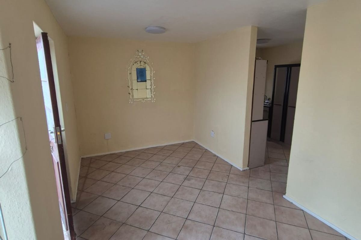 An empty living area featuring ceramic tile flooring and neutral wall finishes, providing a blank canvas for potential interior design updates.