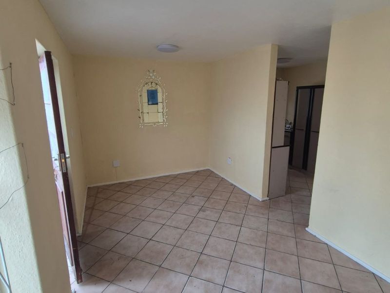 An empty living area featuring ceramic tile flooring and neutral wall finishes, providing a blank canvas for potential interior design updates.