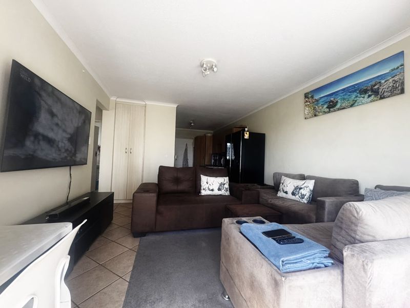 Open-plan living area featuring tiled flooring, built-in storage cupboards, and coved ceiling details, providing a functional space for relaxation and dining.