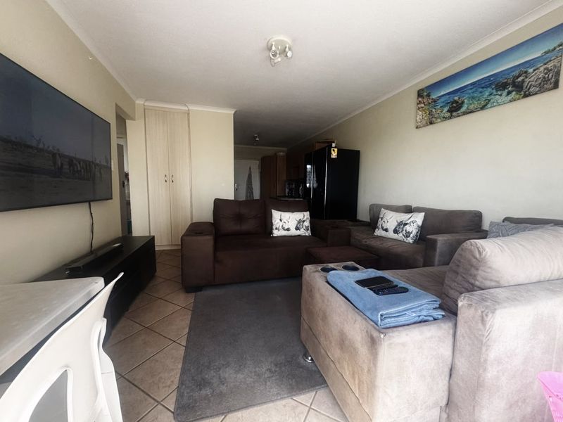 A comfortable living room featuring tiled flooring and a built-in storage cupboard, providing a functional and well-utilized space.