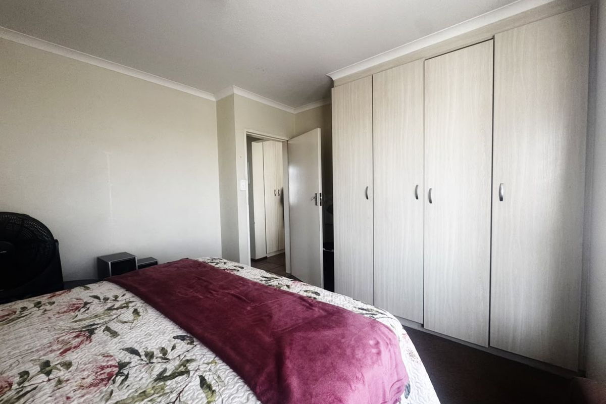 A bedroom featuring light wood-finish built-in cupboards and neutral wall tones, offering a functional and tidy living space.