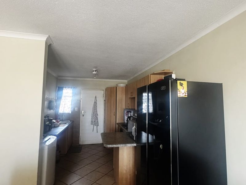 A functional kitchen area featuring built-in cabinetry, laminate countertops, and tiled flooring, offering a practical layout for daily use.