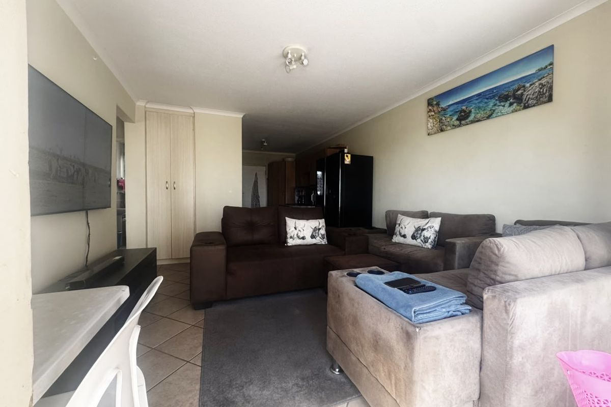 A functional living room featuring tiled flooring, a built-in storage cupboard, and neutral wall finishes, offering a comfortable and practical living space.